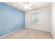 Bedroom featuring a blue accent wall, ceiling fan, and large window at 7966 W Surrey Ave, Peoria, AZ 85381