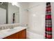 Cozy bathroom with cherry vanity, tile accents, and combined shower-bathtub at 10313 W Windsor Ave, Avondale, AZ 85392