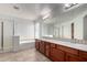 Bright bathroom features a double sink vanity with updated fixtures, tile floors, and a separate shower and bathtub at 10313 W Windsor Ave, Avondale, AZ 85392