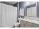 Neutral bathroom featuring a modern vanity with gray cabinets and a decorative arched window above the toilet at 11550 W Mule Deer Ct, Surprise, AZ 85378