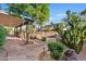 Landscaped backyard featuring mature trees, decorative stone, and a covered patio at 1411 W Mendoza Ave, Mesa, AZ 85202
