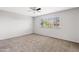 An empty bedroom with carpeted floors and a large window allowing natural light to fill the space at 1411 W Mendoza Ave, Mesa, AZ 85202