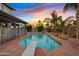 Backyard pool with diving board, rock features, mature palms, and a colorful sunset at 1411 W Mendoza Ave, Mesa, AZ 85202