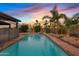 Sparkling pool featuring a diving board, rock features, lush landscaping and a colorful sunset at 1411 W Mendoza Ave, Mesa, AZ 85202