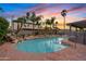 Pool with a rock waterfall feature and mature landscaping at sunset at 1411 W Mendoza Ave, Mesa, AZ 85202