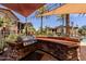 Inviting outdoor kitchen area with stainless steel grill, brick surround, and shade canopies near the community pool at 14250 W Wigwam Blvd # 121, Litchfield Park, AZ 85340