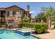 Sparkling community pool with water feature, lush landscaping, lounge chairs, and views of the surrounding buildings at 14250 W Wigwam Blvd # 121, Litchfield Park, AZ 85340