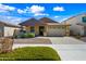 Inviting single-story home featuring a two-car garage, manicured lawn, and a charming front porch with stone accents at 14413 W Eugene Ter, Surprise, AZ 85379