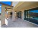 Covered patio features stone flooring, outdoor fireplace with TV, and sliding glass doors to the interior at 14413 W Eugene Ter, Surprise, AZ 85379