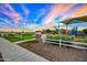 Community playground with covered play structure and manicured landscaping at sunset at 14413 W Eugene Ter, Surprise, AZ 85379