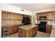 Kitchen showcasing wooden cabinets, a granite island, a wine cooler, and black appliances at 14833 S 14Th Pl, Phoenix, AZ 85048