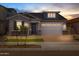 Charming single-Gathering home with a brick driveway, manicured lawn, and a two-car garage at dusk at 15620 W Georgia Dr, Surprise, AZ 85379