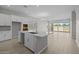 Bright kitchen features a large island with white cabinets and stainless steel sink, with a view to the backyard at 15620 W Georgia Dr, Surprise, AZ 85379