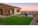 Charming backyard featuring outdoor dining, a cozy fire pit, lush artificial turf and desert landscaping at 15695 W Christy Dr, Surprise, AZ 85379