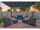 Inviting backyard patio area with custom pergola, stylish seating, lush landscaping and pavers at 15695 W Christy Dr, Surprise, AZ 85379