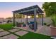 Inviting backyard patio area with custom pergola, stylish seating, lush artificial turf and pavers at 15695 W Christy Dr, Surprise, AZ 85379