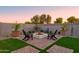 Cozy backyard fire pit area with comfortable seating, lush greenery, and paved patio at 15695 W Christy Dr, Surprise, AZ 85379