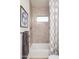 Bright bathroom features a shower over tub with window and neutral toned tile and shower curtain at 15695 W Christy Dr, Surprise, AZ 85379