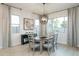 Elegant dining room with a round table, stylish chairs, modern chandelier, and bright natural light from the surrounding windows at 15695 W Christy Dr, Surprise, AZ 85379