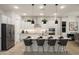 Modern kitchen with white cabinets, stainless steel appliances, and a center island with bar seating and modern hanging lights at 15695 W Christy Dr, Surprise, AZ 85379