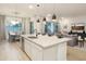Open-concept layout featuring a kitchen island with seating, white cabinetry, pendant lighting, and seamless flow to the living area at 15695 W Christy Dr, Surprise, AZ 85379