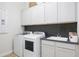 Bright laundry room featuring appliances, ample storage cabinets, and contemporary backsplash at 15695 W Christy Dr, Surprise, AZ 85379