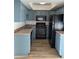A recently remodeled kitchen has black appliances, blue cabinets, laminate countertops and new flooring at 2121 W Royal Palm Rd # 2049, Phoenix, AZ 85021