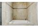 Close-up of a soaking bathtub with stone tile surround and classic gold fixtures, perfect for relaxation at 23214 N 106Th Ave, Peoria, AZ 85383
