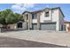 Two-story house featuring neutral tones, stone accents, and a three-car driveway leading to gray garage doors at 23214 N 106Th Ave, Peoria, AZ 85383