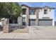 Two-story home with stone accents, neutral paint, and a spacious driveway with gray garage doors at 23214 N 106Th Ave, Peoria, AZ 85383