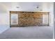 Large, light-filled living room with a full stone accent wall, two windows, and soft carpet flooring for added comfort at 23214 N 106Th Ave, Peoria, AZ 85383