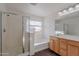 Bathroom featuring wood cabinetry, shower with glass door, soaking tub and ample lighting at 30944 N Bramwell Ave, San Tan Valley, AZ 85143