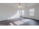 Light-filled bedroom featuring dark wood floors, three windows, and a modern ceiling fan at 30944 N Bramwell Ave, San Tan Valley, AZ 85143