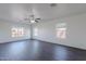 Living room featuring modern dark wood-look flooring, three windows, and a ceiling fan at 30944 N Bramwell Ave, San Tan Valley, AZ 85143