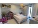 Charming bedroom with a chandelier and shelves displaying dolls, including a playhouse, with large bright window at 3669 E Boot Track Trl, Gilbert, AZ 85296