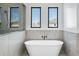 Bright bathroom featuring a soaking tub with marble surround and black hardware with two windows at 3933 E Freeman Ln, San Tan Valley, AZ 85140