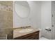 Close-up of the bathroom vanity featuring granite countertop and round mirror at 5038 N 20Th Ave, Phoenix, AZ 85015