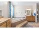 Bathroom with a garden tub, natural light, tile floors, and a vanity with wood cabinets at 5221 N Tuthill Rd, Litchfield Park, AZ 85340