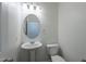 This half bathroom features a pedestal sink, oval mirror, and toilet at 8854 W Aster Dr, Peoria, AZ 85381