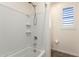 Bright bathroom featuring a tiled tub-shower combination and a shuttered window for natural light at 9342 W White Feather Ln, Peoria, AZ 85383