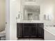 Bathroom vanity features dark cabinets, neutral countertop, and large mirror with towel and bath access at 9342 W White Feather Ln, Peoria, AZ 85383