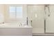 Bright bathroom features a luxurious tub, glass-enclosed shower, and plantation shutters for natural light at 9342 W White Feather Ln, Peoria, AZ 85383