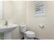 A neutral toned half bathroom featuring a round mirror, white toilet, and a small window for natural light at 9342 W White Feather Ln, Peoria, AZ 85383