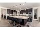 Well-lit kitchen featuring an island with barstool seating, dark cabinets, stainless appliances and granite countertops at 9342 W White Feather Ln, Peoria, AZ 85383
