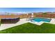 Landscaped backyard with a refreshing pool, comfortable lounge seating, and an artificial grass lawn at 9342 W White Feather Ln, Peoria, AZ 85383