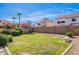 Backyard featuring lush greenery, palm trees, a large grassy area, and block perimeter wall at 10517 W La Reata Ave, Avondale, AZ 85392