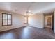 Living room with wood-look floors, ceiling fan, shuttered windows, and access to other rooms at 10517 W La Reata Ave, Avondale, AZ 85392