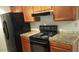 Efficient kitchen with wooden cabinetry, granite countertops and black appliances at 10610 S 48Th St # 1074, Phoenix, AZ 85044