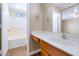 Bathroom featuring a vanity with wood cabinets, a sink, and a view of the bathtub with a door at 12450 W Hearn Rd, El Mirage, AZ 85335