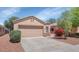 Single-story home featuring a two-car garage, desert landscaping, and a tile roof at 12450 W Hearn Rd, El Mirage, AZ 85335